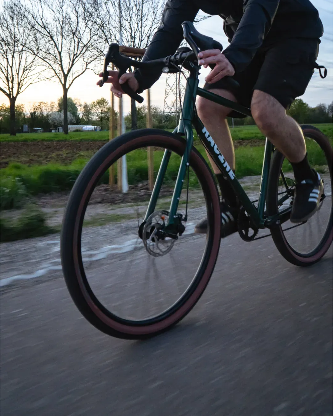 Cycliste au coucher du soleil sur une route de campagne, vélo Racine vert