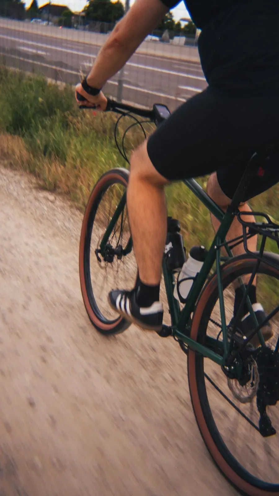 Cycliste de dos sur une piste, vélo Racine vert équipé d’un porte-bagages
