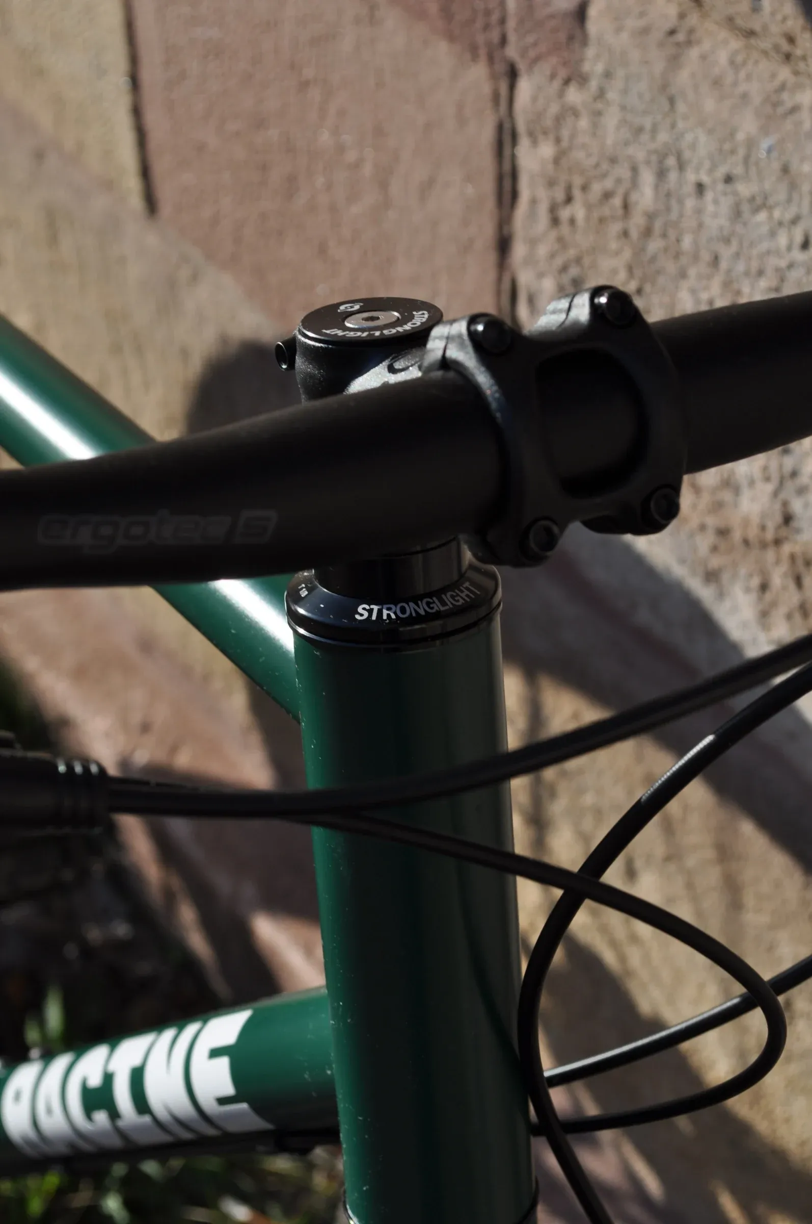 Potence et guidon noir du vélo Vélos-Racine, cadre vert mousse en arrière-plan, détail serrage et géométrie
