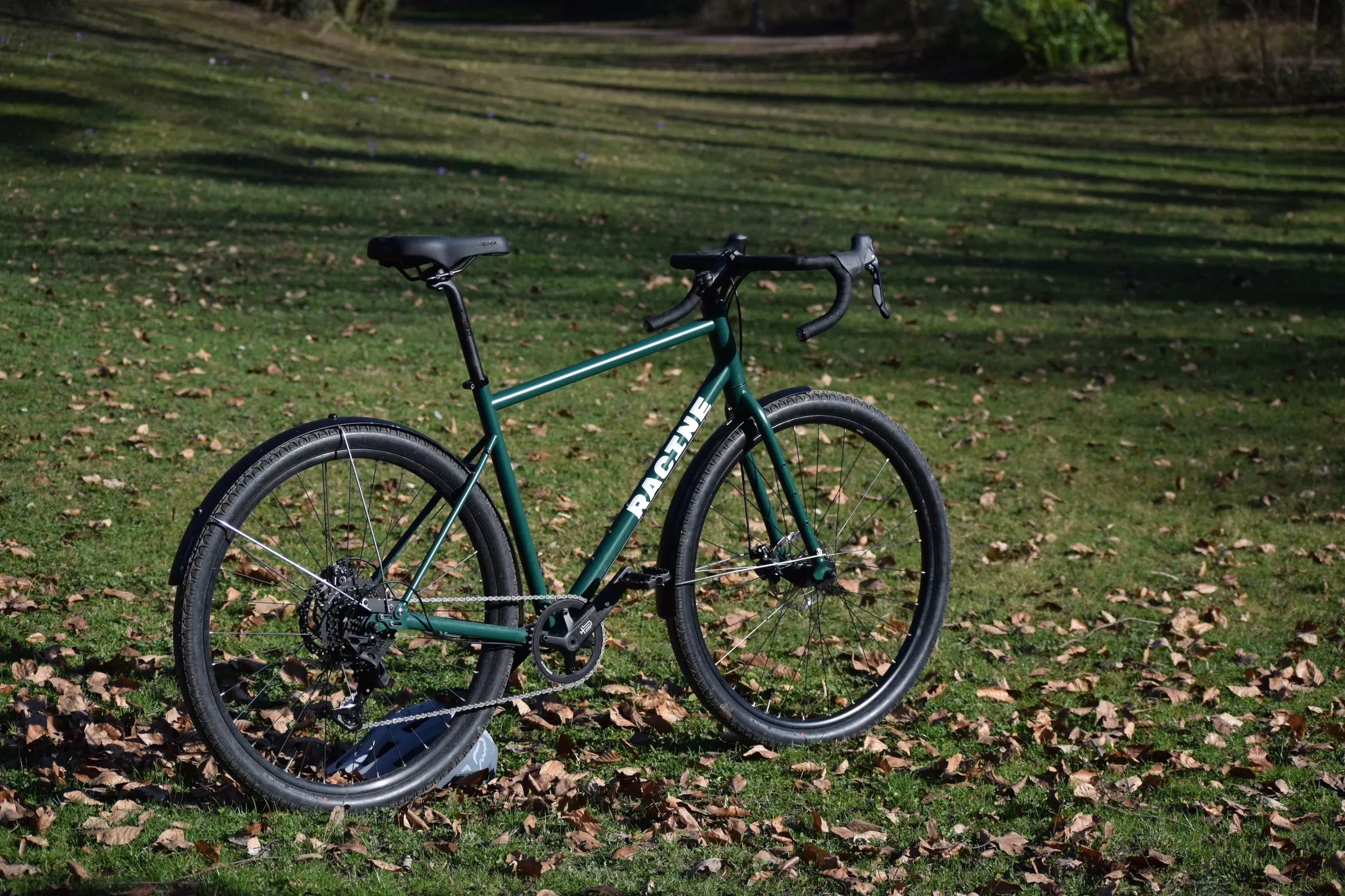 Vélo Racine vert mousse de profil sur une pelouse d'automne, cintre drop bar et freins à disque